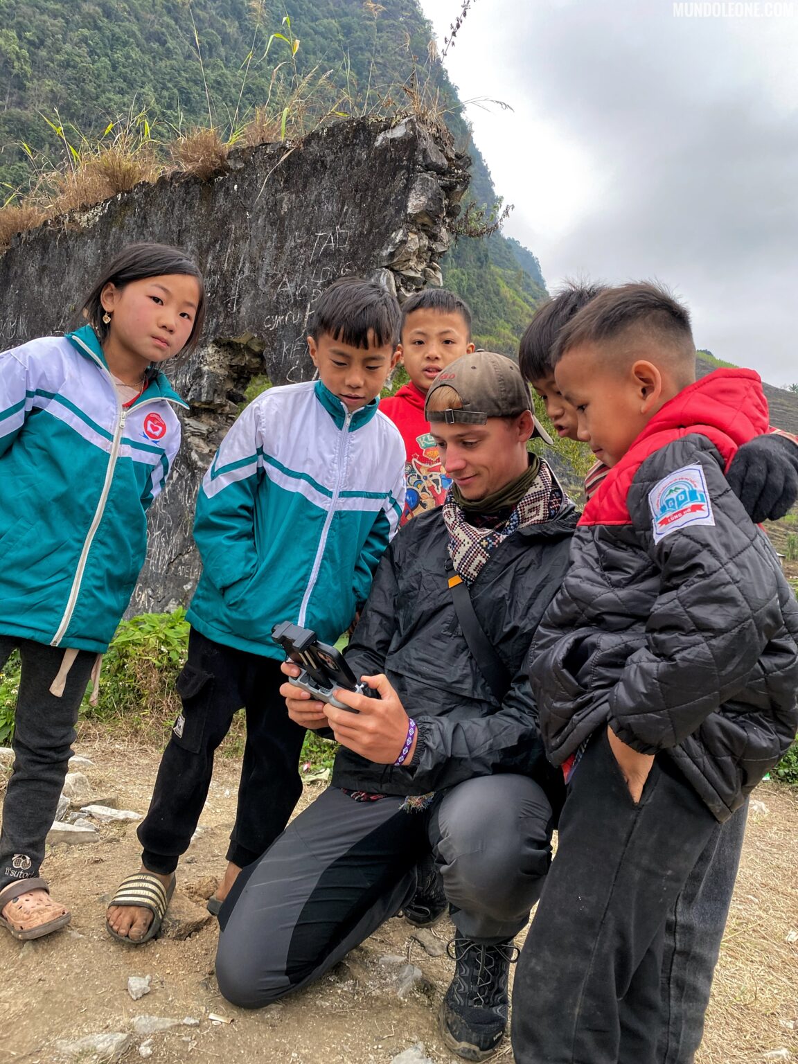 Man showing drone footage to local children in the mountains of Ha Giang, Northern Vietnam.