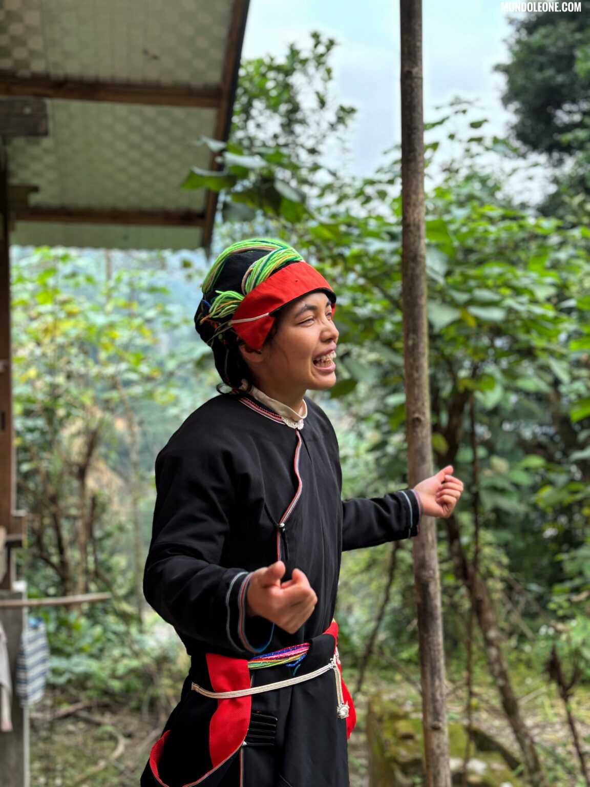 Bikki in traditional Ha Giang dress, smiling in front of a lush green background at her jungle homestay.